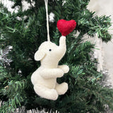 White elephant ornament with a red heart on a Christmas tree
