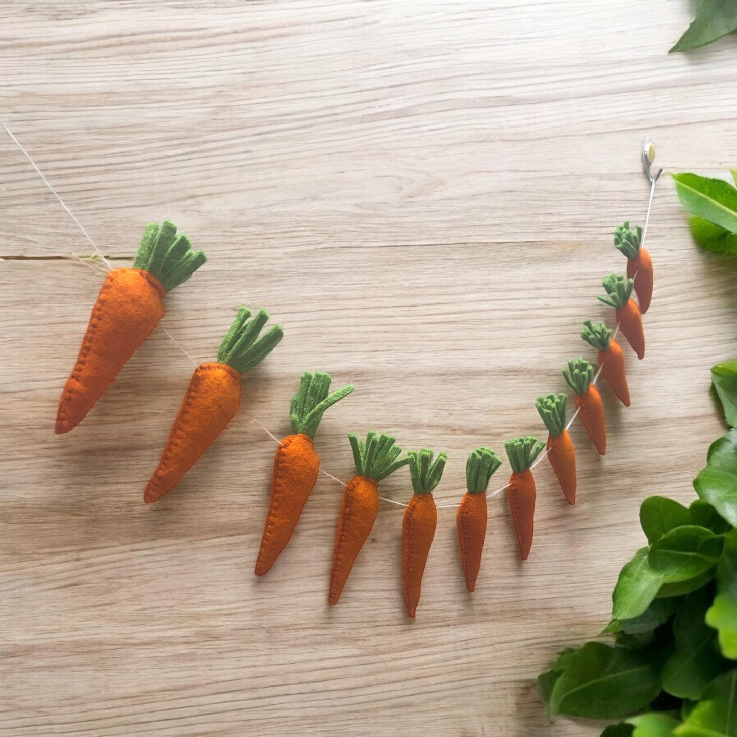 Carrot-shaped decorations on a wooden surface with green leaves.