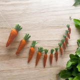 Carrot-shaped decorations on a wooden surface with green leaves.