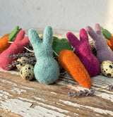 Colorful felted bunny and carrot toys on a wooden surface with lavender sprigs.