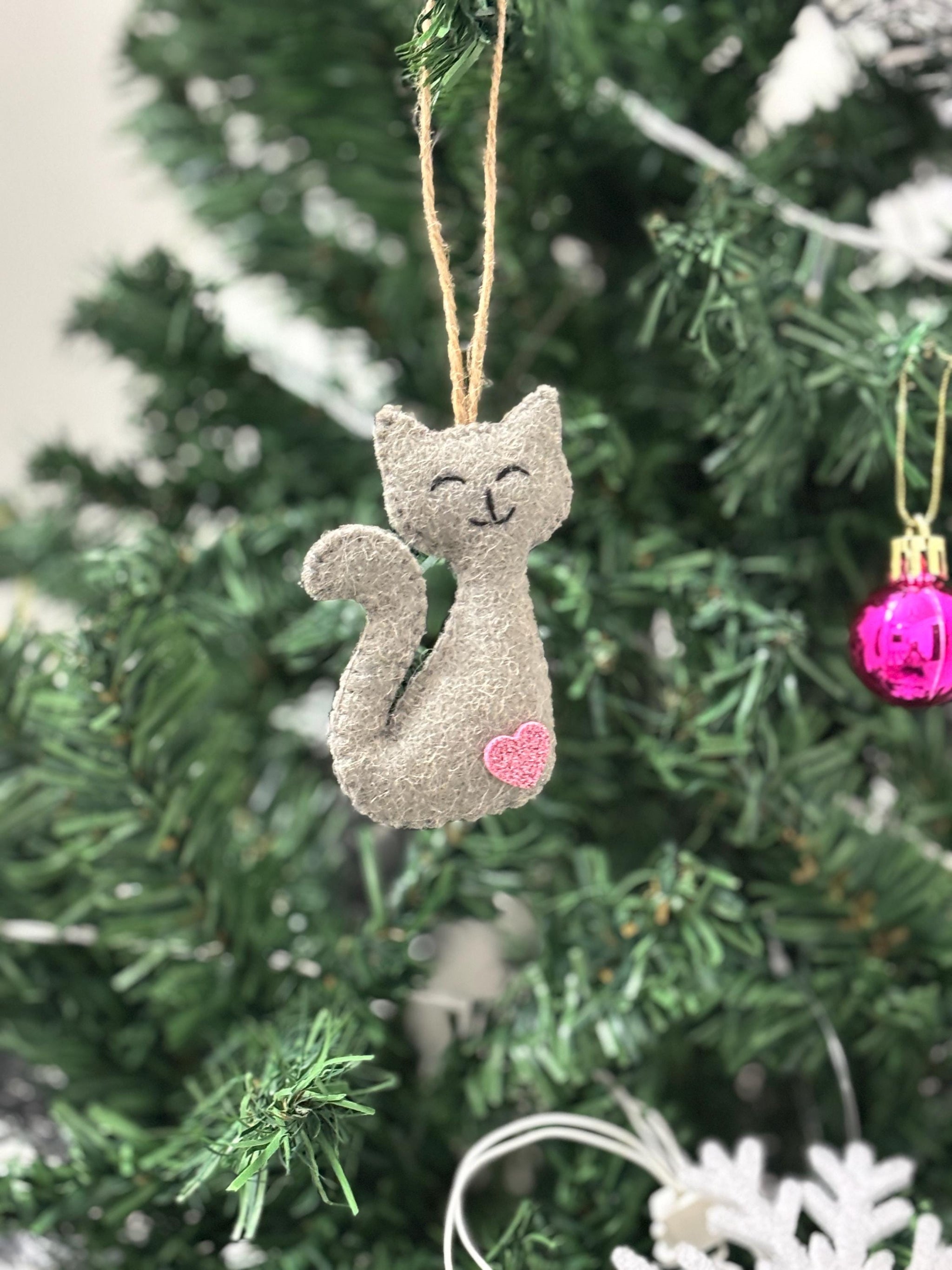 Cat-shaped ornament with a pink heart on a Christmas tree