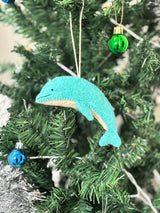 Teal dolphin ornament hanging on a Christmas tree with green and blue glass balls.