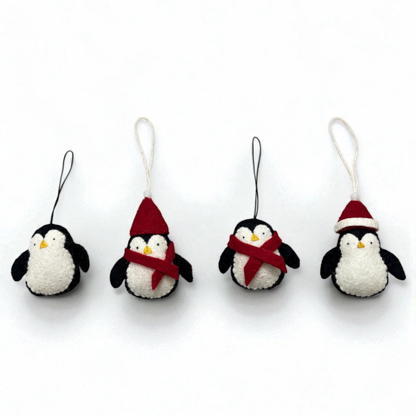 Four penguin ornaments with scarves and hats on a white background