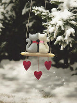 Decorative hanging cat ornament with red hearts against a snowy background