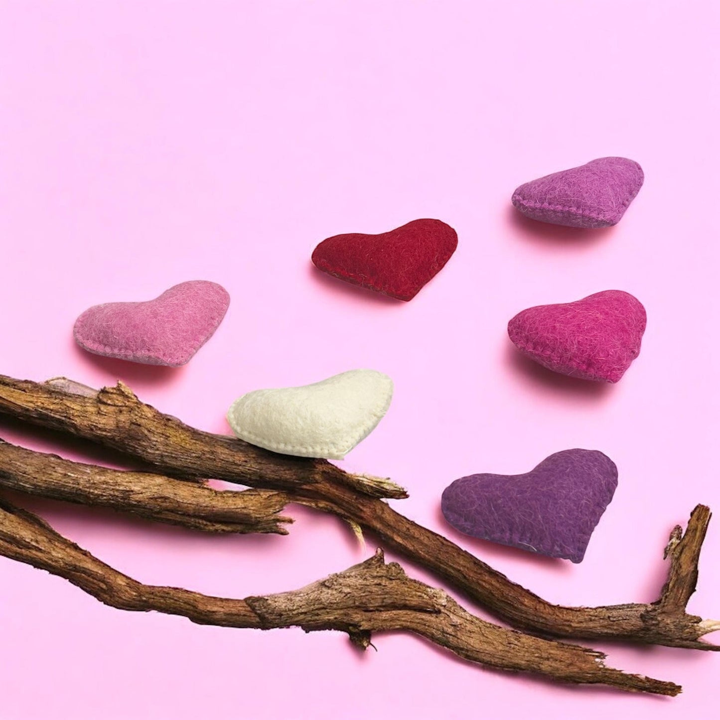 Heart-shaped objects on a branch with a pink background