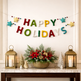 Decorative setup with 'Happy Holidays' sign, poinsettia arrangement, and lanterns on a table.