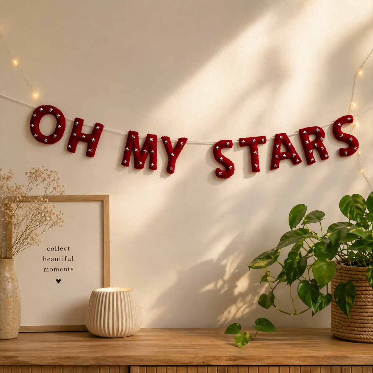 Decorative string with 'OH MY STARS' letters on a wall with plants and a framed picture.