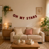Living room with 'OH MY STARS' decorative banner on the wall, beige sofa with pillows, and wooden coffee table.