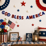 Decorative setup with 'GOD BLESS AMERICA' banner, American flags, and patriotic elements on a wall.