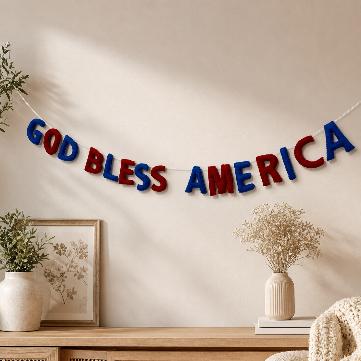 Decorative banner with 'GOD BLESS AMERICA' on a wall above a wooden console table.