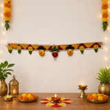 Decorative setup with marigold flowers, candles, and a garland on a white wall.