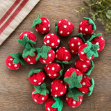 Felt strawberries with white polka dots on a wooden surface
