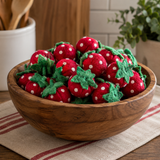 Wooden bowl filled with red and white polka dot strawberry-shaped objects on a kitchen counter.