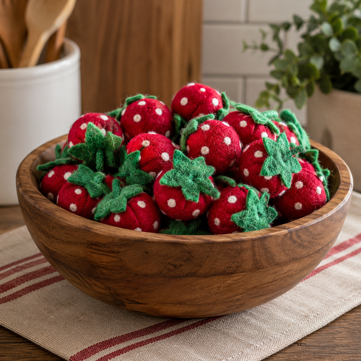 Wooden bowl filled with red and white polka dot strawberry-shaped objects on a kitchen counter.