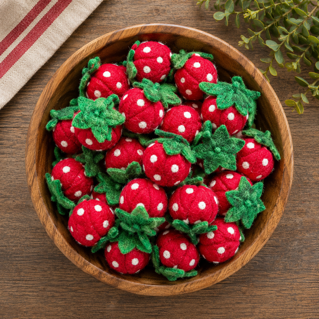 Wooden bowl filled with red and white polka dot strawberries on a wooden surface.