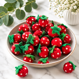 Felt strawberries with white polka dots on a marble surface with greenery.