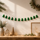 Decorative green tree garland on a wall with home decor items below.