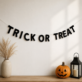 Halloween-themed decor with 'TRICK OR TREAT' banner, pumpkin, and lantern on a wooden surface.