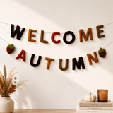 Decorative banner with 'Welcome Autumn' text hanging on a wall with autumn-themed decor.