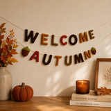 Decorative autumn banner with 'Welcome Autumn' on a wall with a pumpkin, candle, and books.
