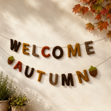 Decorative banner with 'Welcome Autumn' text on a wall with autumn leaves.
