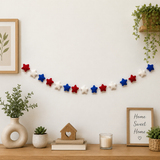 Decorative string with red, white, and blue stars on a wall above a wooden shelf with plants and decor items.