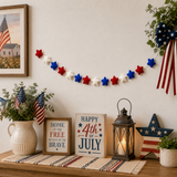 Decorative setup with American flags, stars, and 'Happy 4th of July' sign on a table.