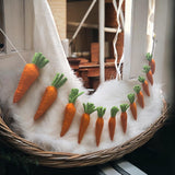 Felt carrot decorations on a white fur surface with a blurred indoor background