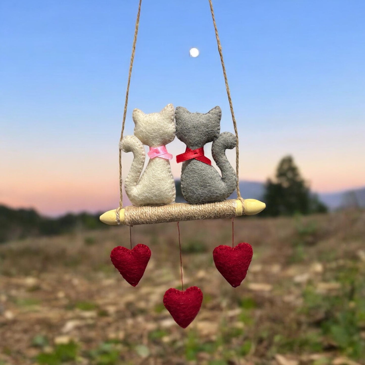 Two stuffed animals on a swing with heart decorations against a natural background