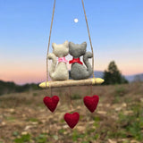 Two stuffed animals on a swing with heart decorations against a natural background