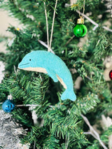 Blue dolphin ornament hanging on a Christmas tree with other decorations.