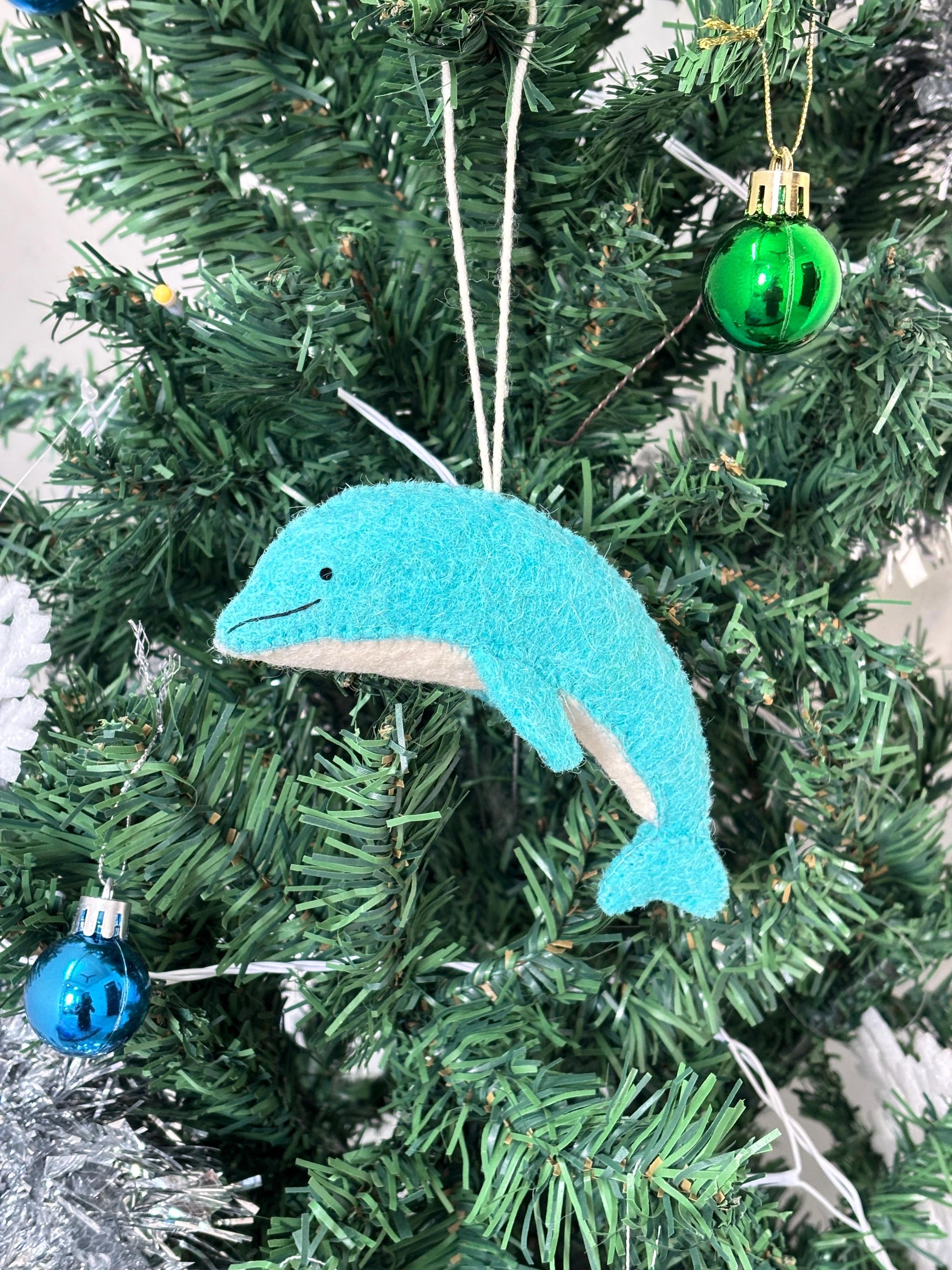 Blue dolphin ornament on a Christmas tree with other decorations.