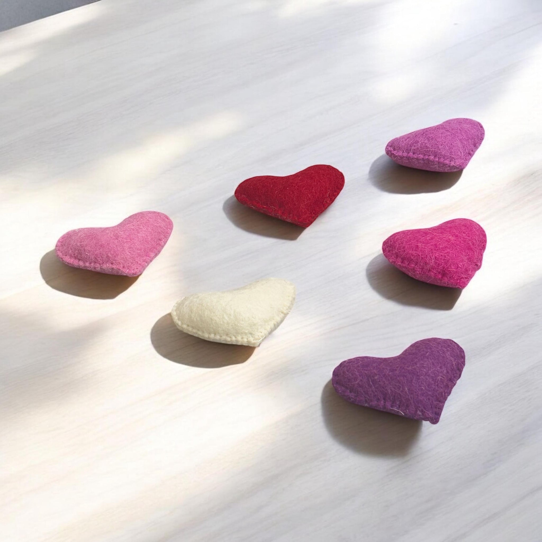 Heart-shaped cushions in pink, red, white, and purple on a light surface