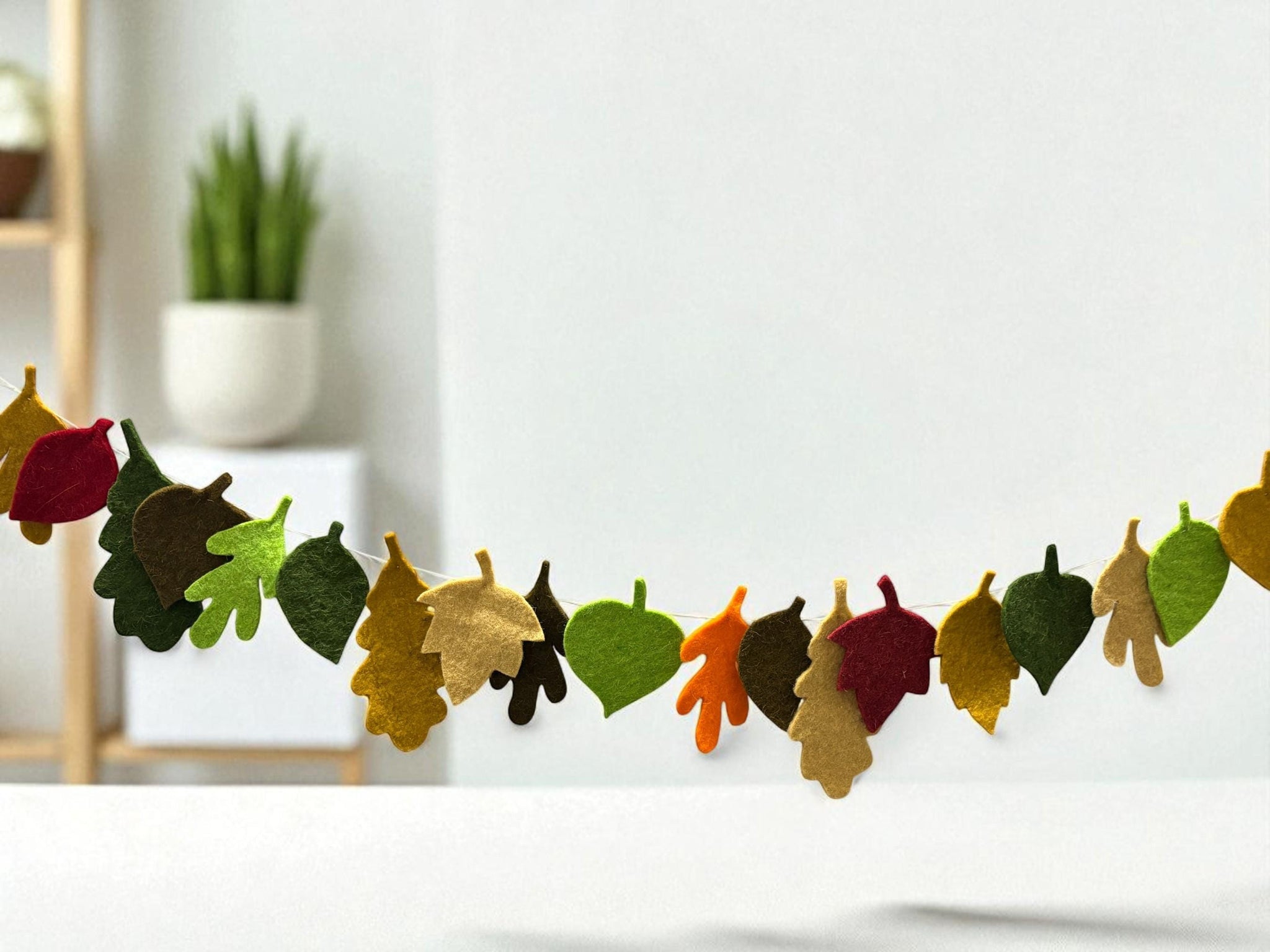 Decorative leaf garland on a white wall with a blurred indoor background